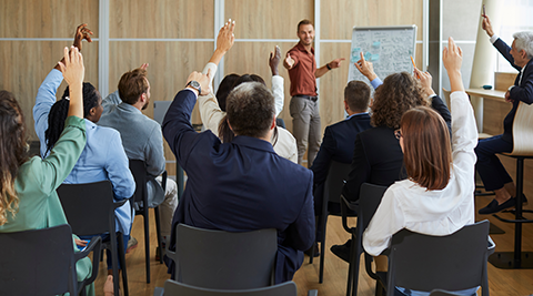 Classroom with teacher and students raising their hands